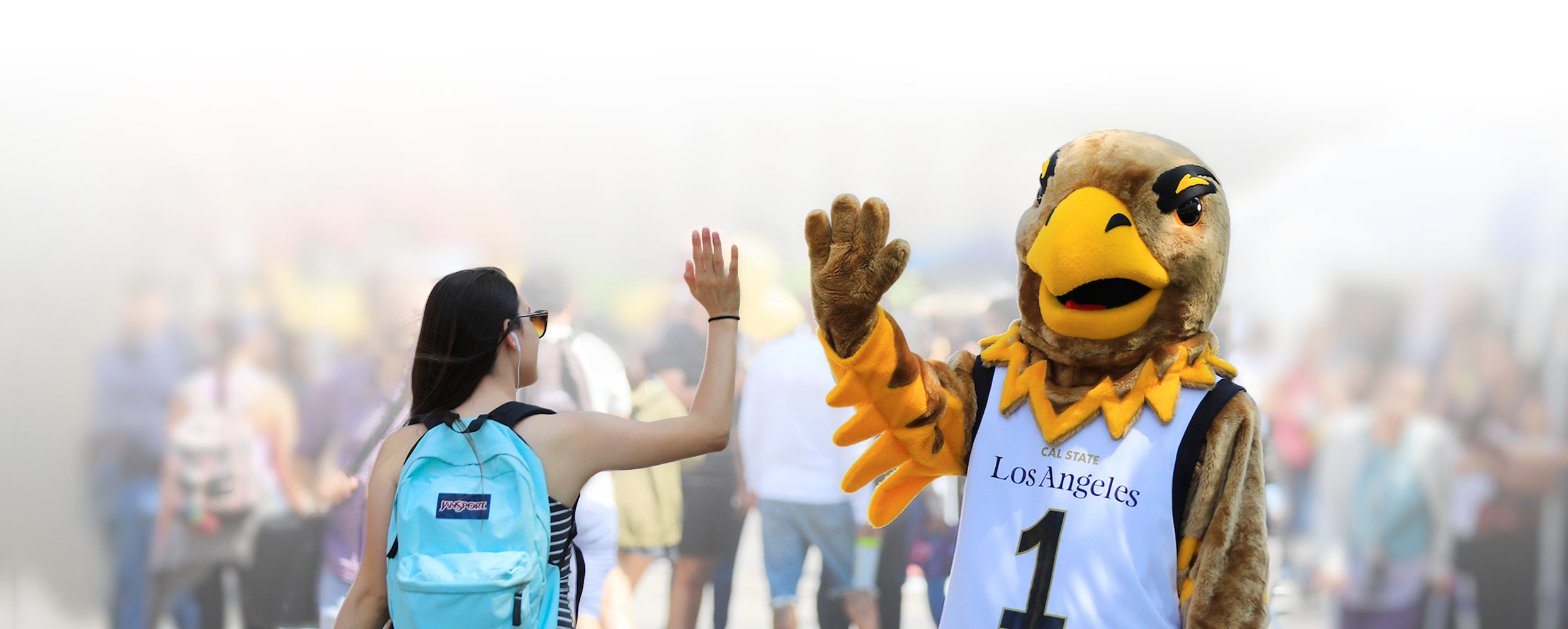 Cal State LA student giving a high-fave to Eddie the Golden Eagle